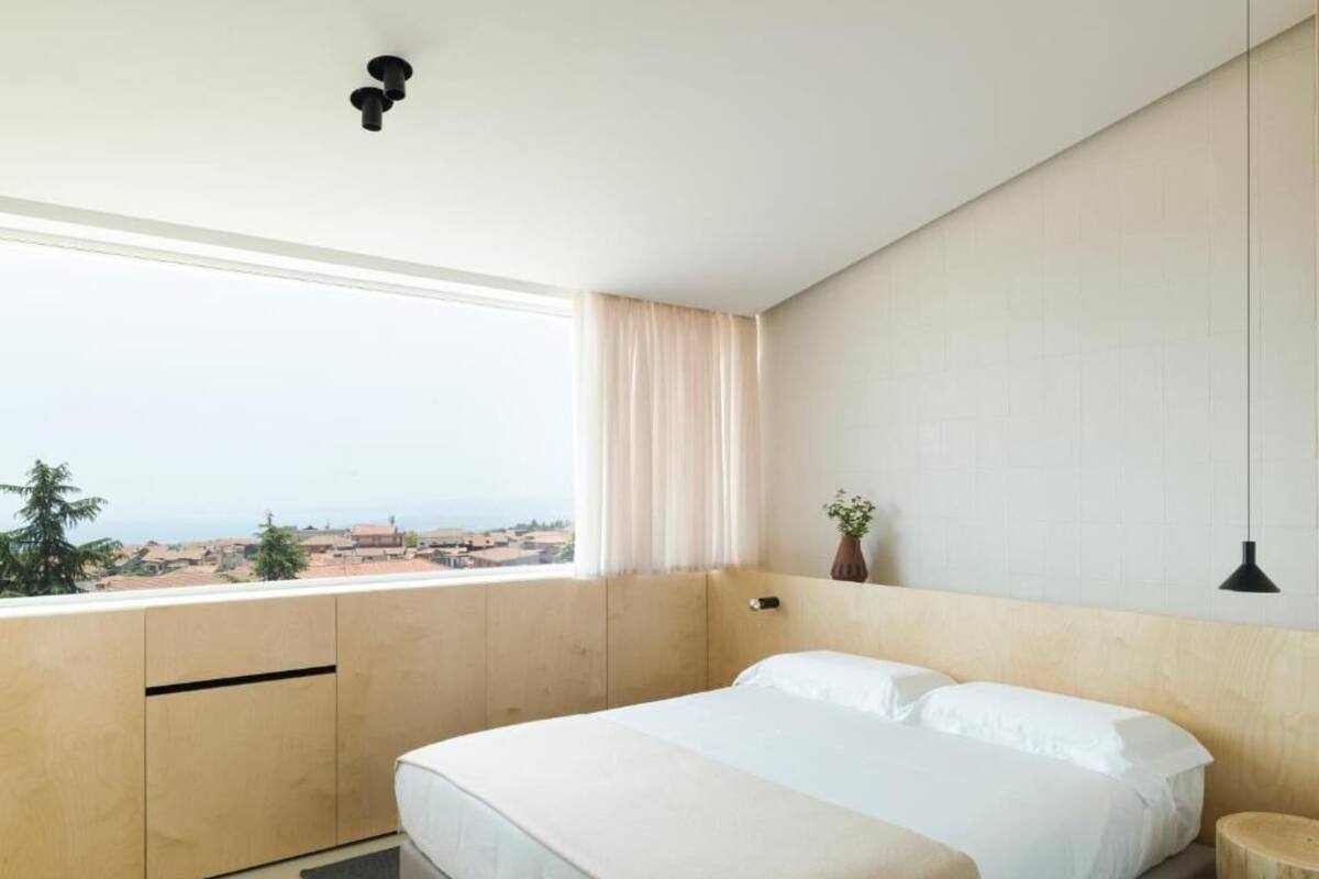 Een slaapkamer met een groot bed, uitzicht op de stad en een raam met gordijnen.