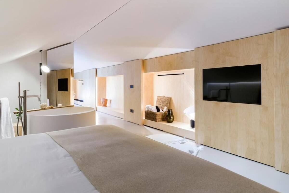 Een moderne hotelkamer met een groot bed, een ingebouwd bad en een flatscreen televisie aan de muur.