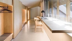 Ein modernes Interieur mit einem langen, schmalen Flur, Holzmöbeln und großen Fenstern.