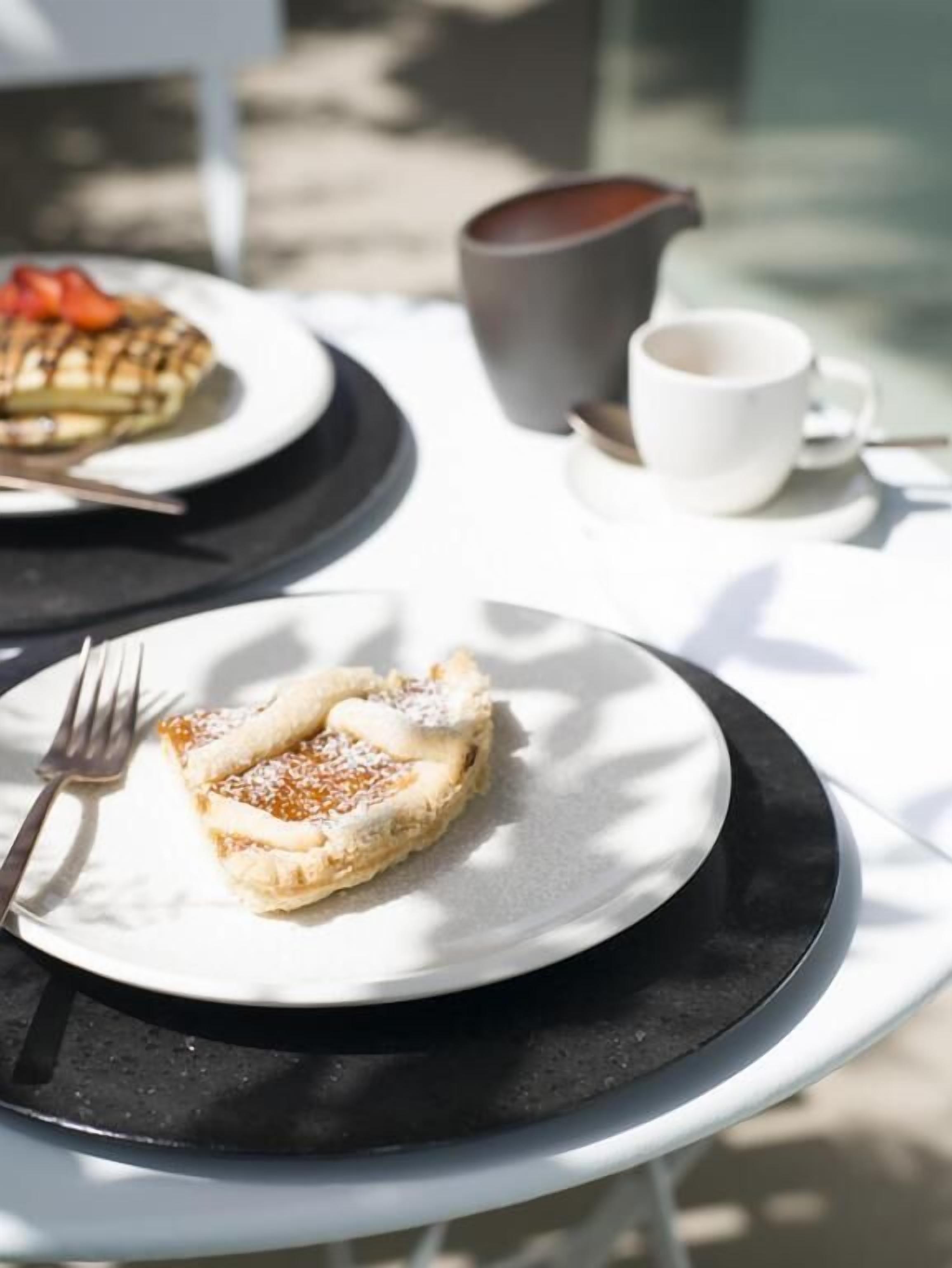 Una mesa con un plato de comida, una taza y una jarra.