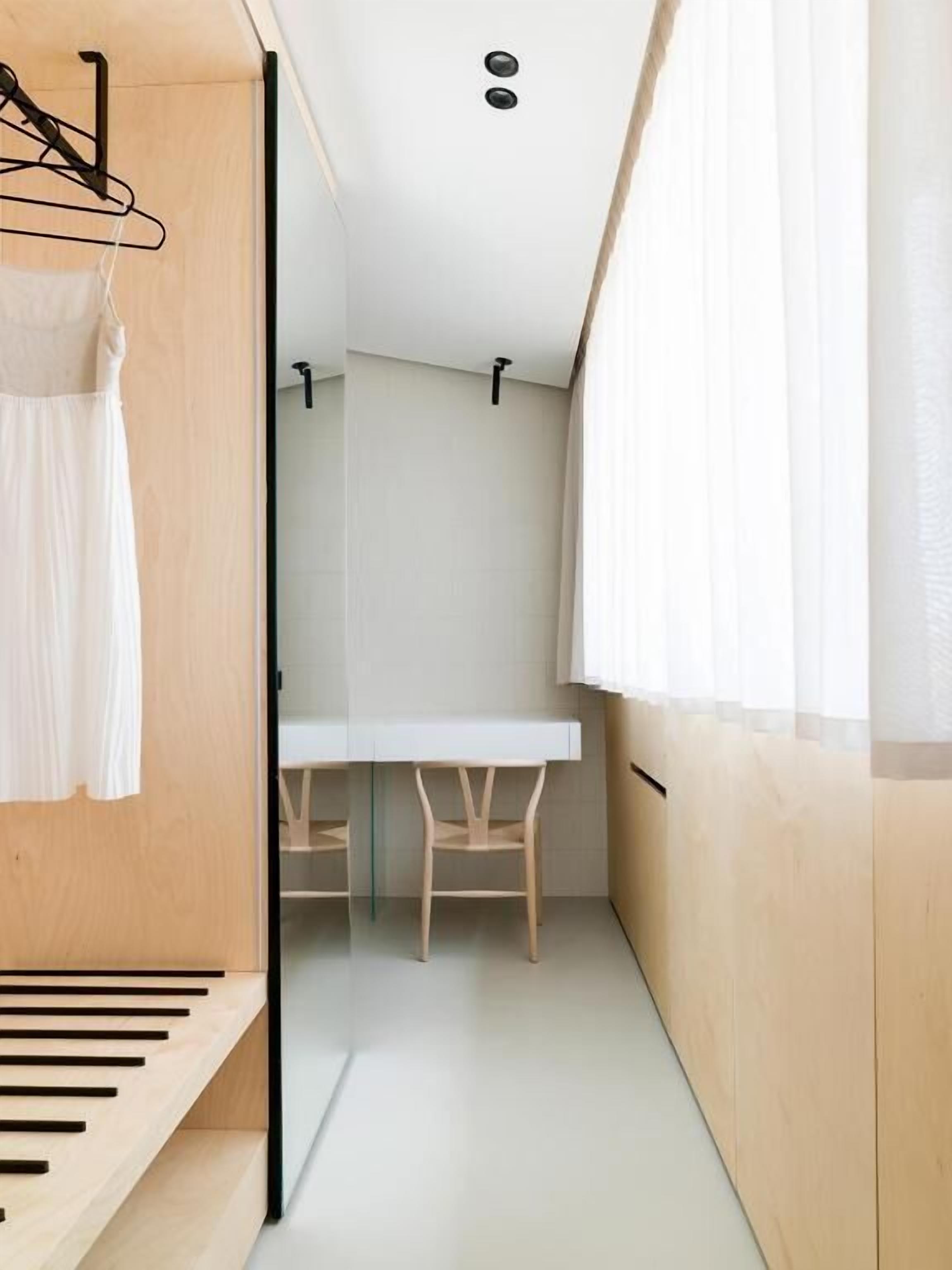 A modern, compact room with a wooden bench, a small table, and chairs.