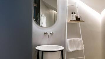 Une salle de bain moderne avec un miroir rond, un lavabo blanc et un porte-serviettes blanc.