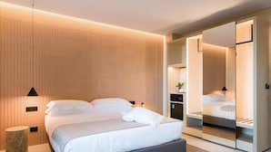Ein modernes Schlafzimmer mit einem großen Bett, einem Nachttisch, einem Beistelltisch und einem Kleiderschrank mit Spiegel.