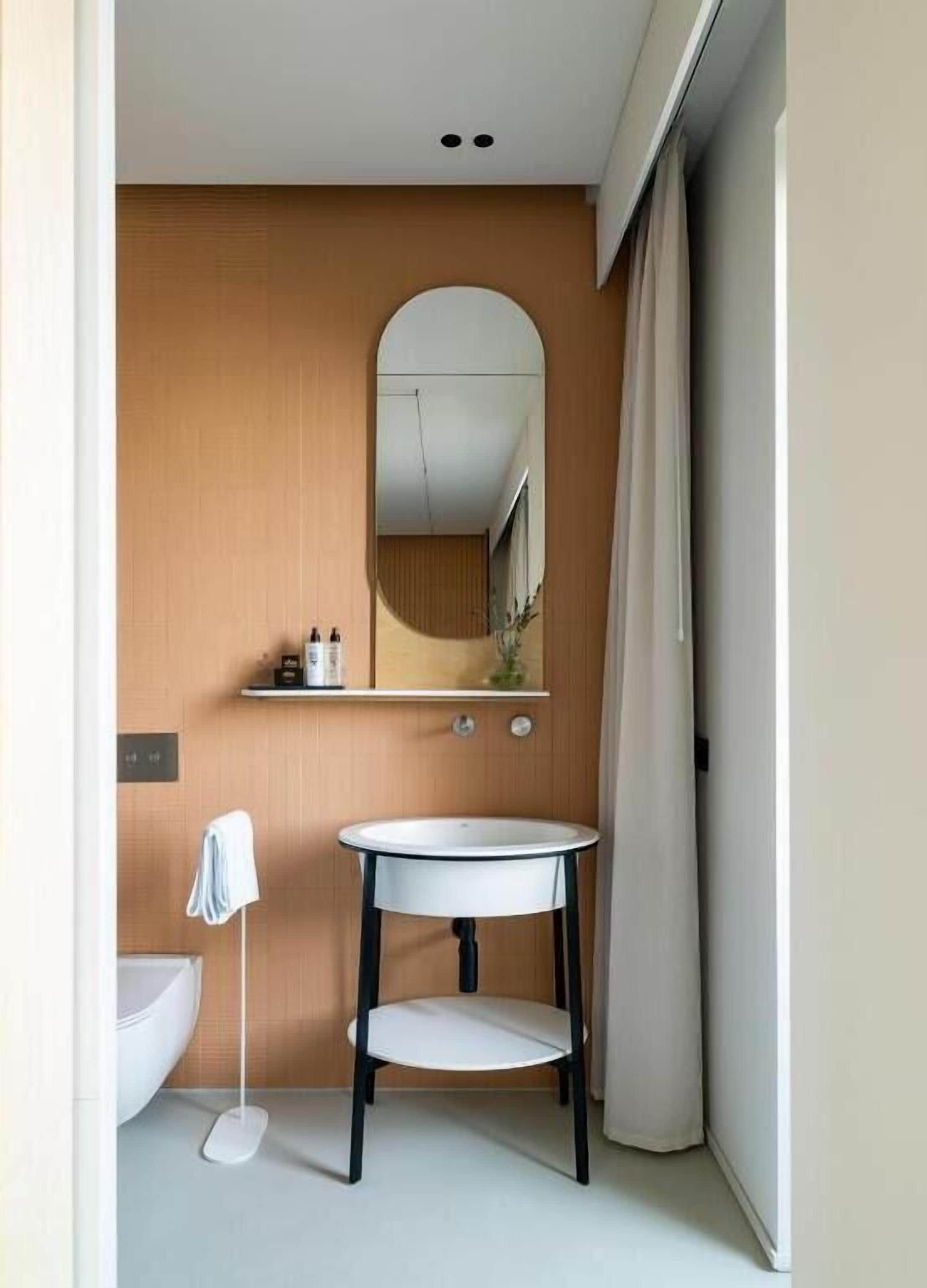 Un baño pequeño con un lavabo redondo, un espejo y un inodoro.