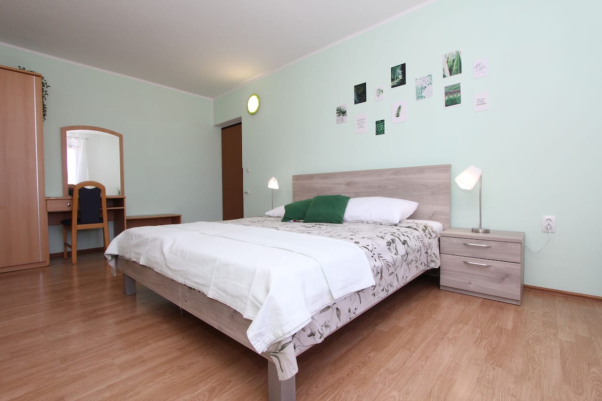 A bedroom with a bed, bedside tables, a desk, a chair, and a wardrobe.