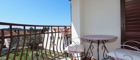 Un balcón con vistas a casas, una mesita y dos sillas.