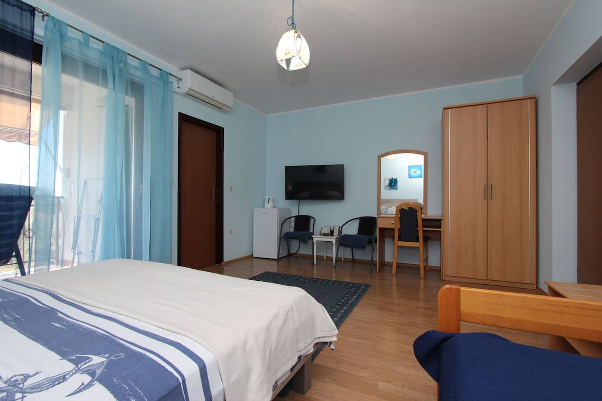 A bedroom with a bed, a desk, a chair, a wardrobe, and a television.