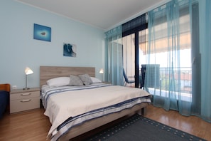 Un dormitorio con cama, mesitas de noche, una silla y vistas al exterior.
