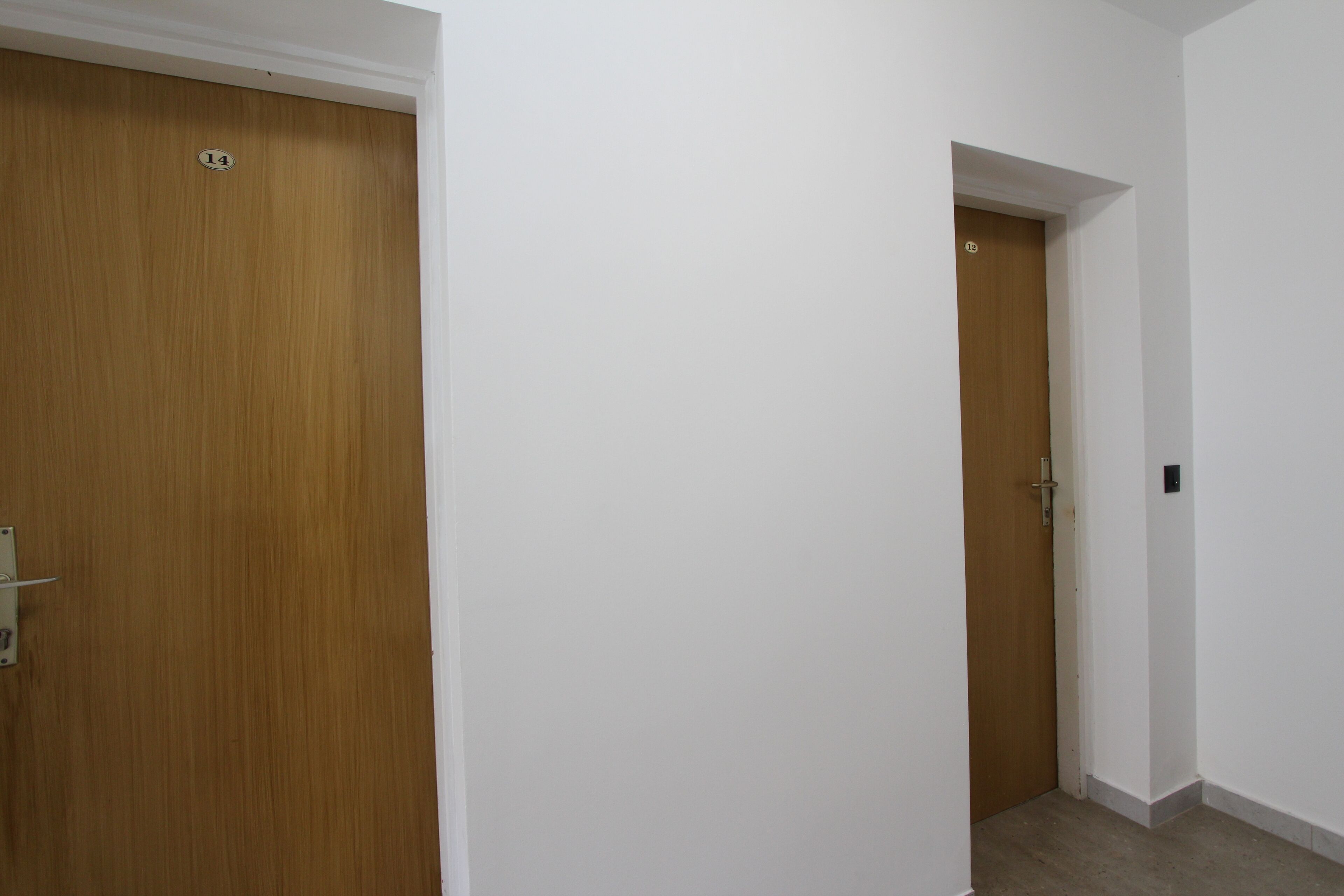 A hallway with a wooden door labeled '14' and a white wall.