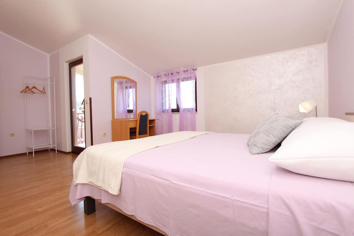 A bedroom with a bed, a desk, a chair, a wardrobe, and a mirror.
