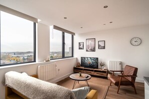 Una sala de estar moderna con un ventanal grande, un sofá, un televisor y una silla.