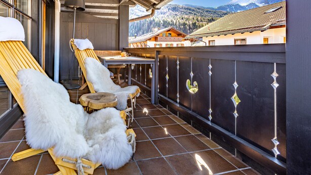 A balcony with wooden loungers and a table, overlooking a mountain landscape. - Stylish Alpine Retreat for 4 – Walk to Slopes with Alpspitze Views & Balcony (Garmisch-Partenkirchen)