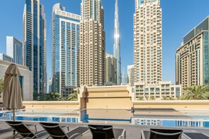 A rooftop pool area with lounge chairs and a view of high-rise buildings.