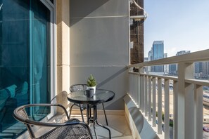 A balcony with a table and chairs, a small potted plant, and a view of the city skyline.