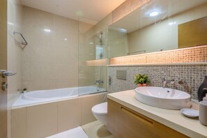 A modern bathroom with a glass-enclosed shower, a freestanding bathtub, a white sink, and a wooden vanity.