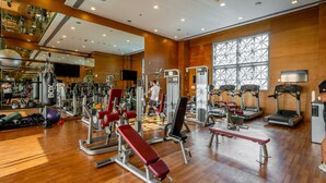 A gym with various exercise equipment, a large mirror, and a wooden floor. - The Burj Khalifa Collection (Dubai)