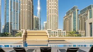 A rooftop pool with lounge chairs, surrounded by high-rise buildings and palm trees. - The Burj Khalifa Collection (Dubai)