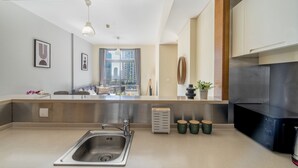 A modern kitchen with a stainless steel sink, a built-in oven, and a window overlooking a cityscape. - The Burj Khalifa Collection (Dubai)