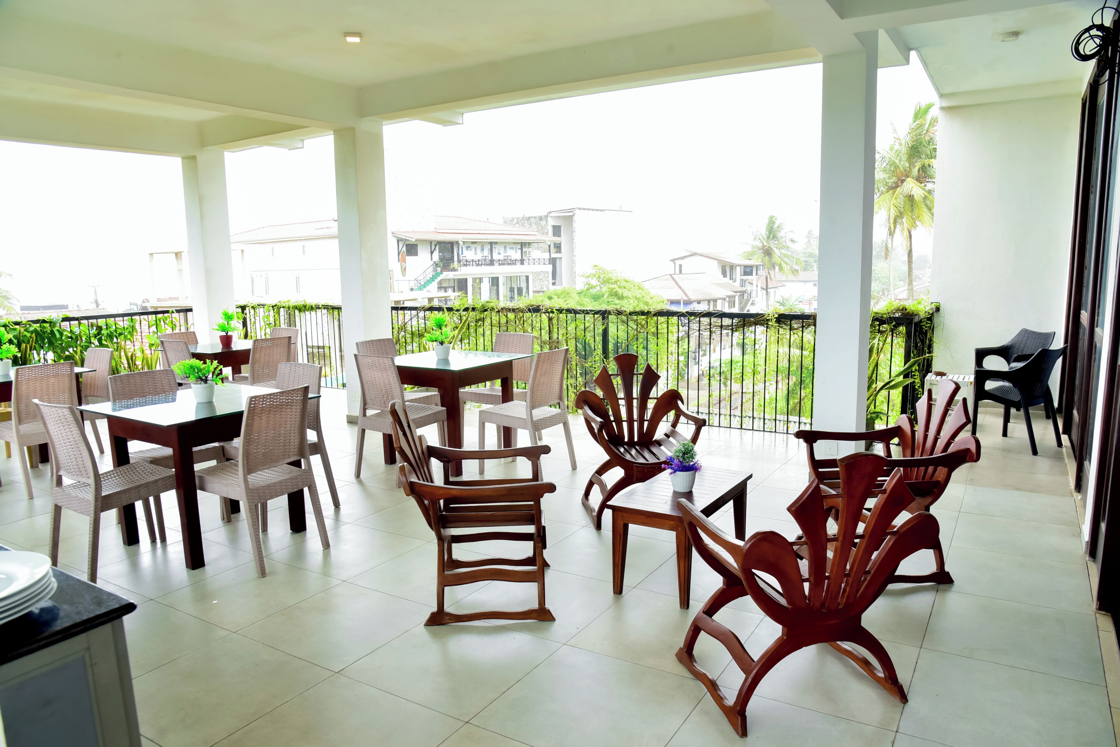 A spacious balcony with a dining area, chairs, and potted plants.