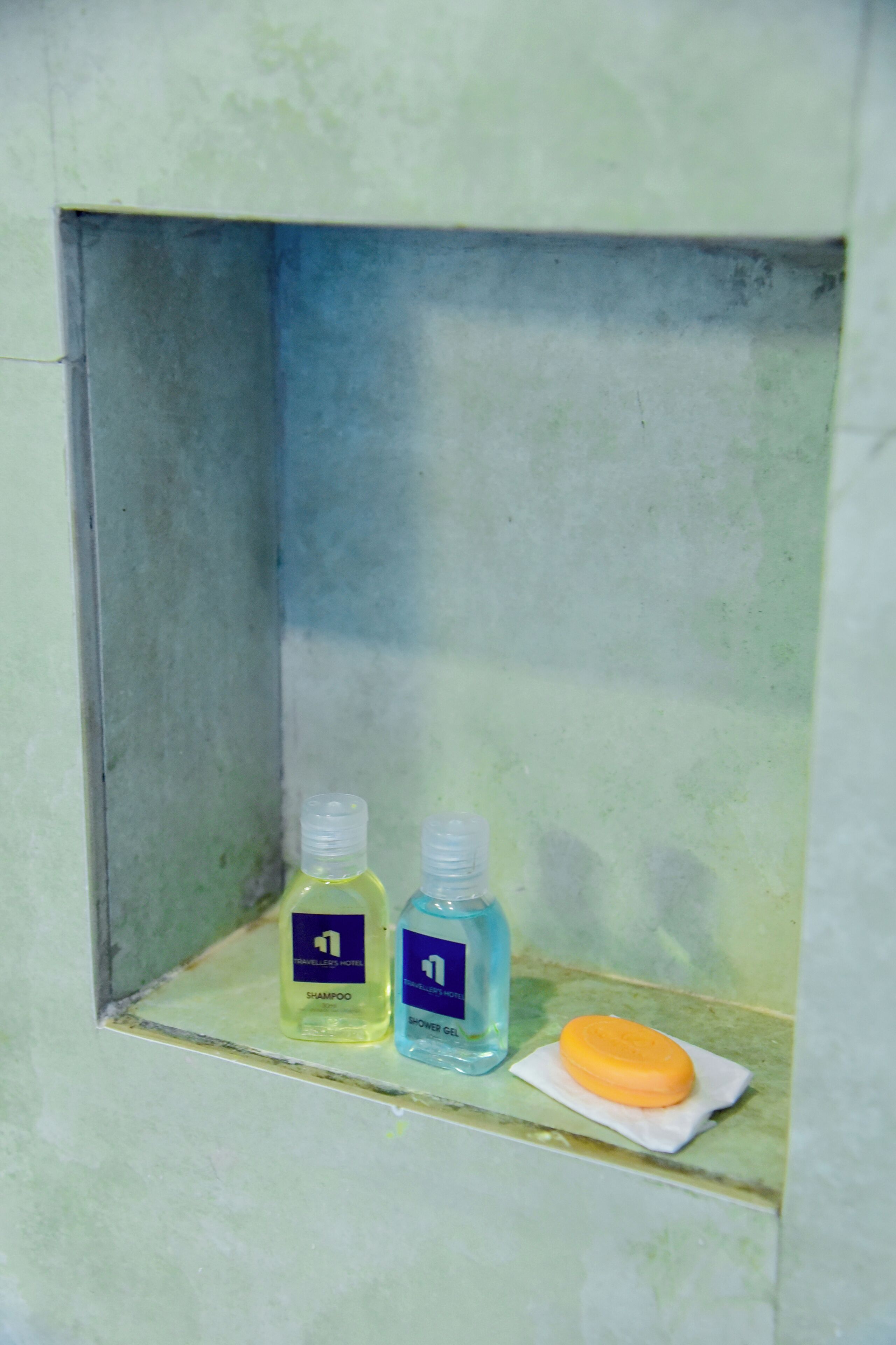 Un estante de baño con dos botellas de artículos de tocador y una pastilla de jabón.