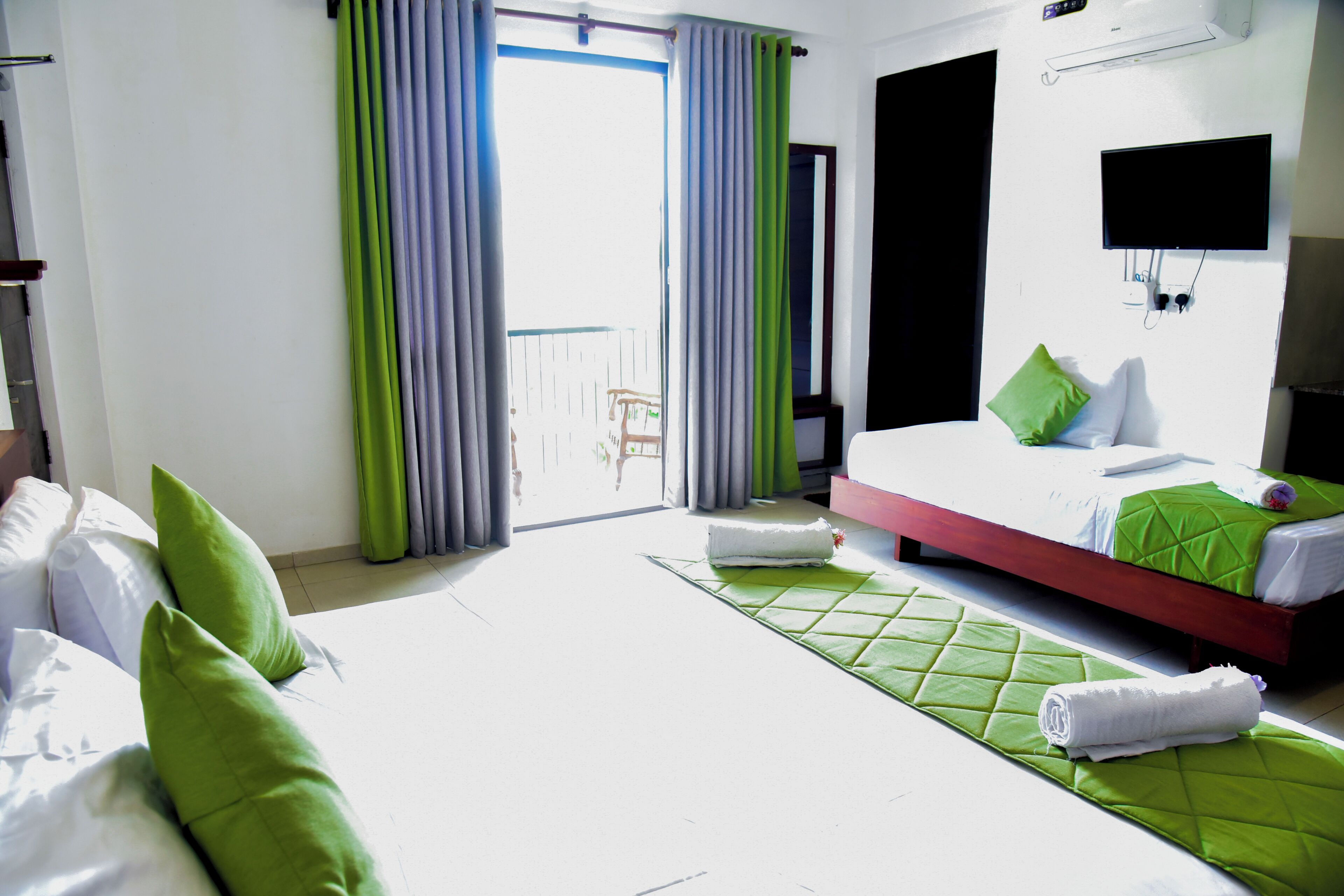 Una habitación de hotel con cama, una silla, un televisor y una ventana con cortinas.