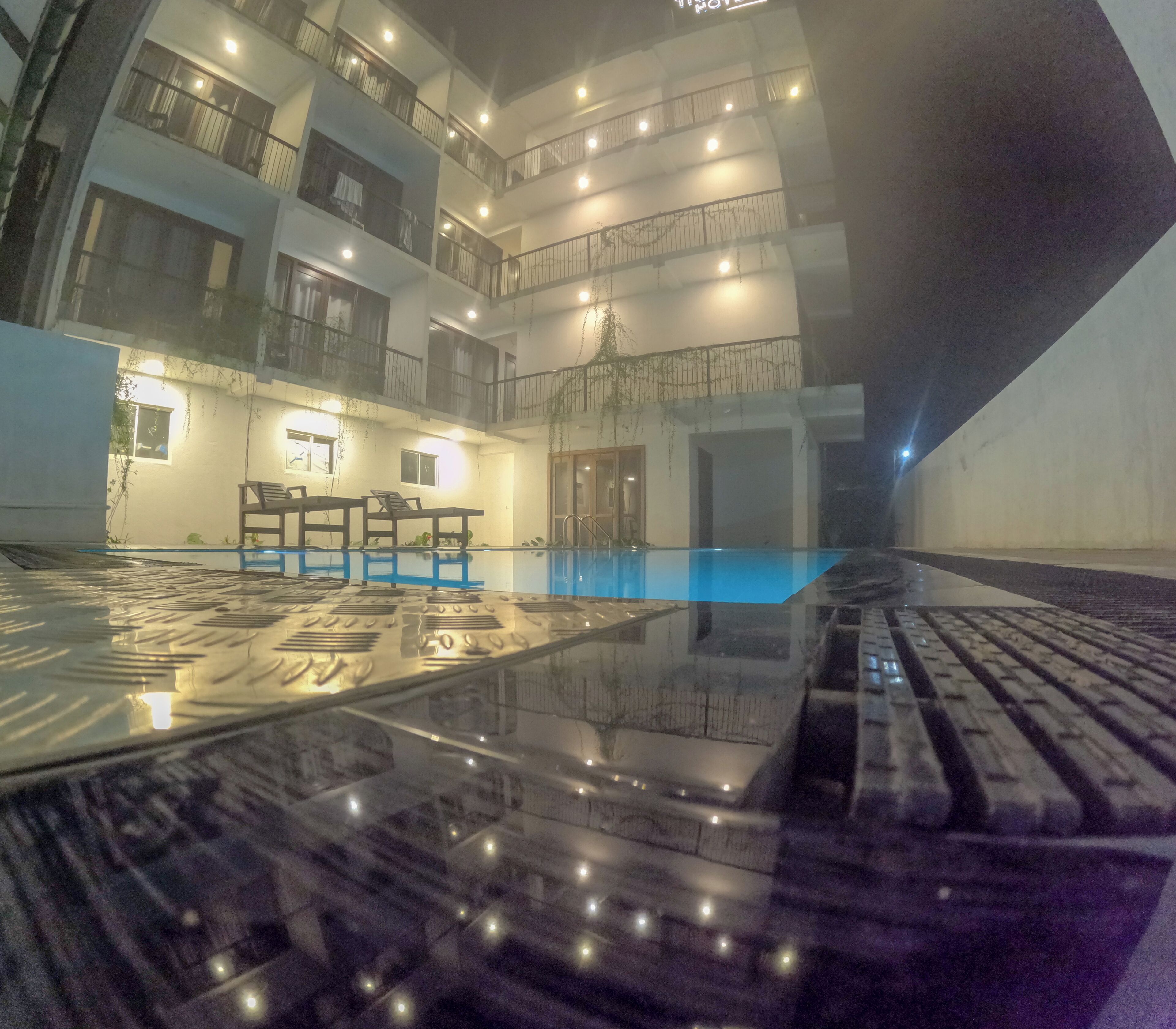 A multi-level hotel interior with a swimming pool, balconies, and a staircase.