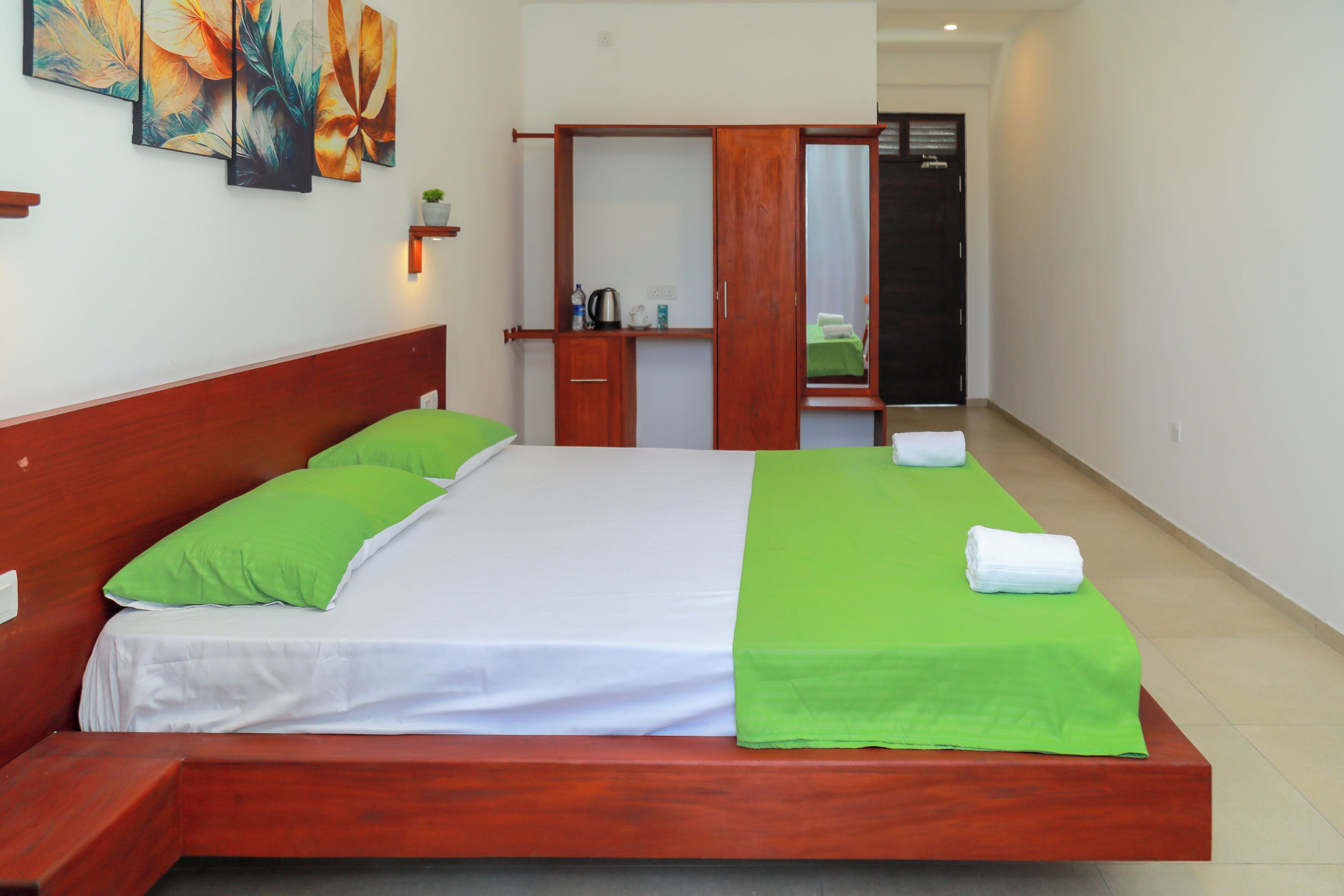 A neatly made bed with green and white bedding, a wooden headboard, and a green throw blanket.
