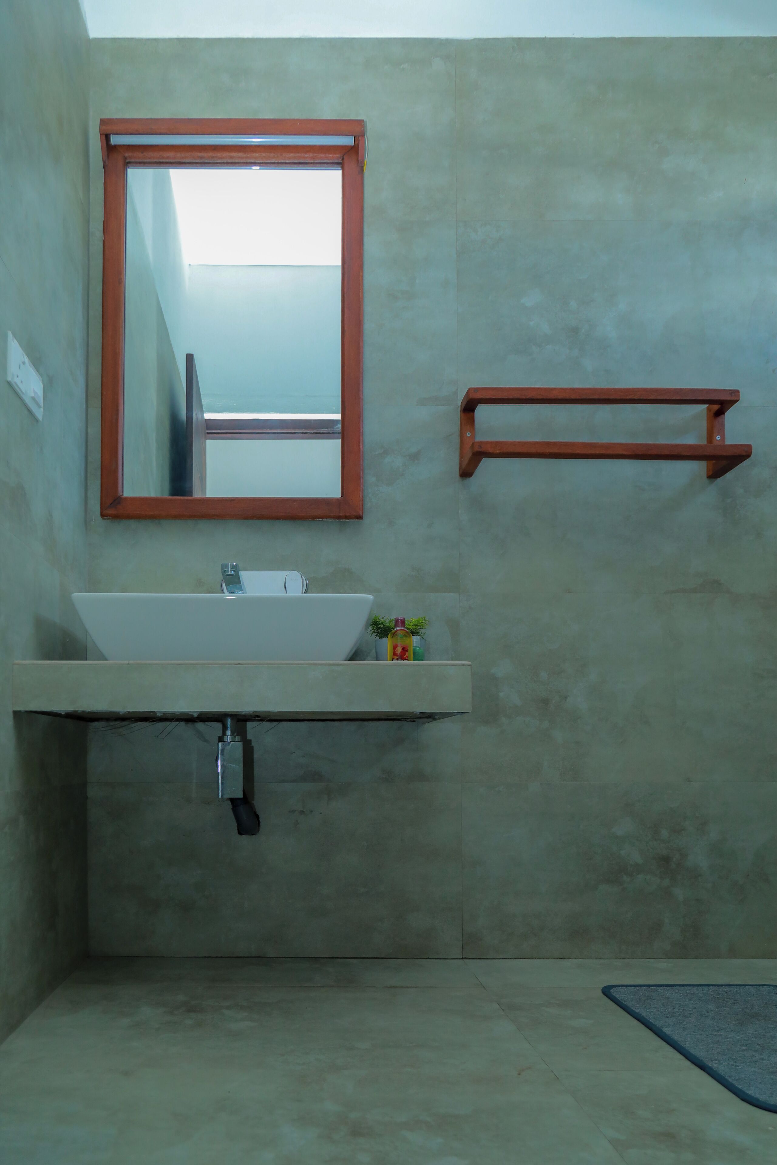 A bathroom with a large mirror, a white sink, and a small shelf.