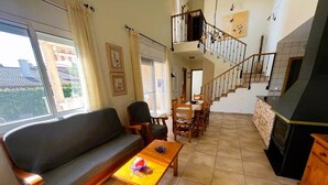 Ein großzügiger Wohnbereich mit Sofa, Esstisch, Stühlen und einer Treppe.