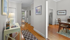 A hallway with a dining area, a kitchen, and a living space.