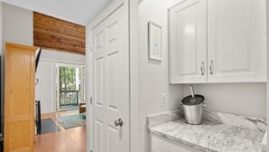 A kitchen with white cabinets, a marble countertop, and a pot on the counter.