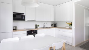 Una cocina moderna con armarios blancos, microondas, tostadora y cafetera.