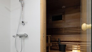 Un cuarto de sauna con un banco de madera, un cabezal de ducha y un cubo.