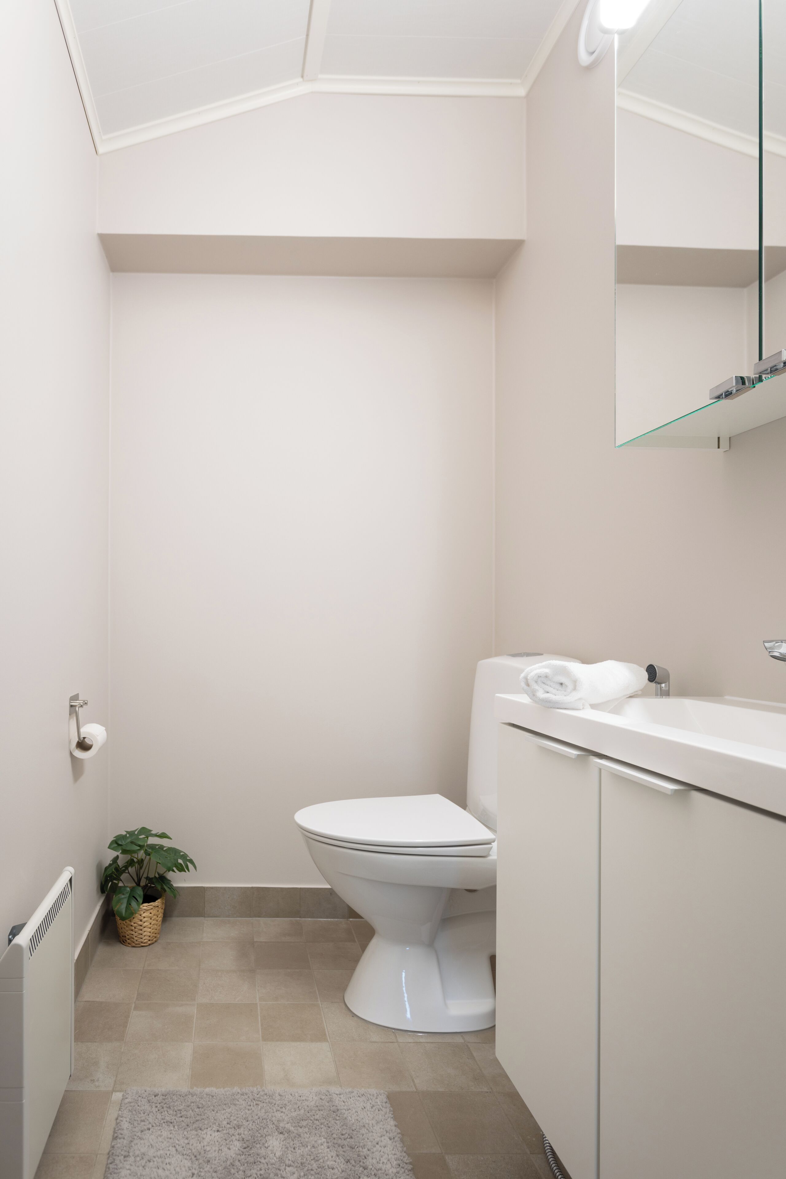 Ein kleines, modernes Badezimmer mit Toilette, Waschbecken und Spiegel.