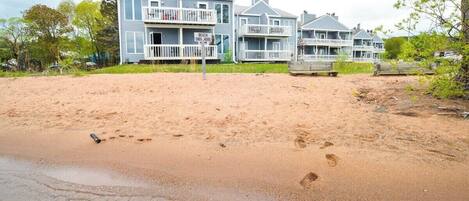 En fastighet vid stranden med flera hus, en sandstrand och en skylt som visar var stranden slutar.