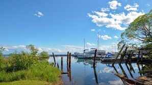 A marina with boats docked, calm water, and a clear sky.