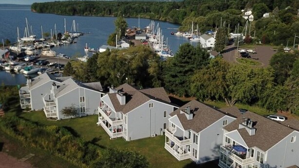 A marina with multiple boats and a row of white buildings with balconies. - Bayfield Condo 1BR + Loft | Lake Superior View (Bayfield)