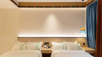 Una habitación de hotel con dos camas, una mesita de noche con teléfono y una lámpara.