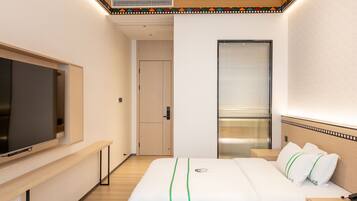 Una habitación de hotel con una cama, un televisor, una ventana con persianas y una puerta que da a otra habitación.