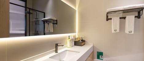 A modern bathroom with a large mirror, a sink, and a towel rack.