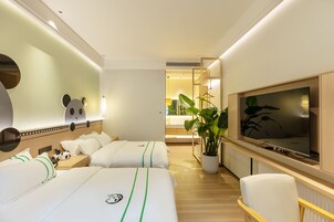Una habitación de hotel con dos camas, televisor, escritorio y planta en maceta.