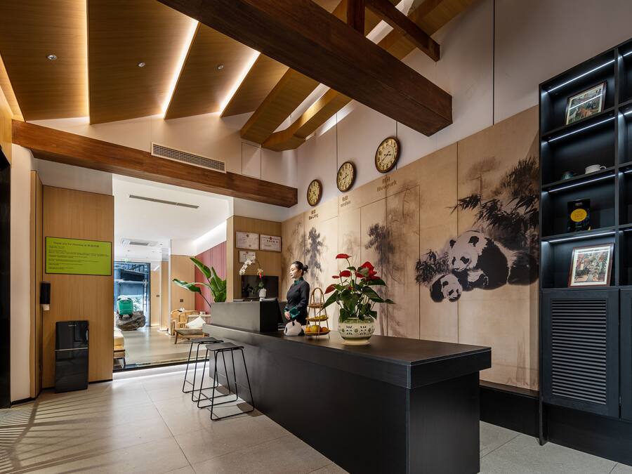 A reception area with a wooden ceiling, a reception desk, and a wall with clocks and artwork.
