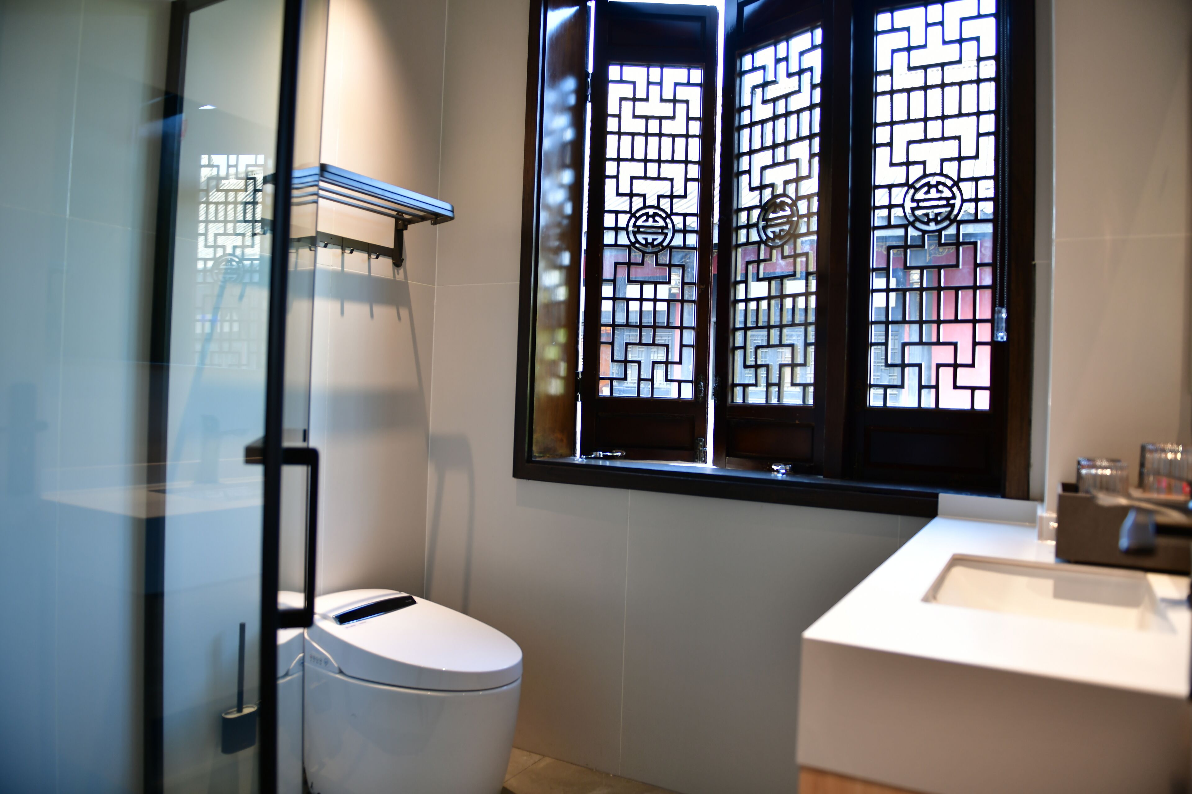 A modern bathroom with a glass shower enclosure, a white toilet, and a sink with a mirror.