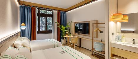 A hotel room with two beds, a TV, a desk, and a bathroom.