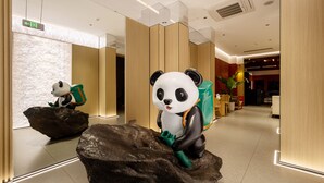 A reception area with a large panda statue on a rock, wooden paneling, and a modern interior design. - XISHU GARDEN INN (Chengdu)