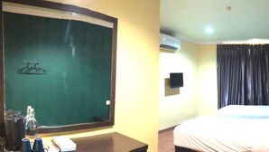 A hotel room with a bed, a desk with a chair, a mirror, an air conditioning unit, and a window with curtains. - Hotel Sunjoy9 Klang (Klang)