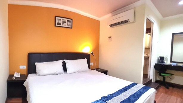 A hotel room with a bed, a bedside lamp, a phone on the nightstand, and a desk with a chair. - Hotel Sunjoy9 Klang (Klang)