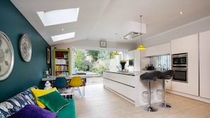 Een moderne keuken met witte kastjes, een zwarte oven en een geel hanglamp.