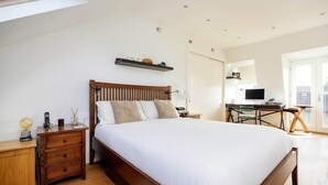 A bedroom with a wooden bed, a desk, and a chair. - The Tranquil Townhouse, by Veeve (London)