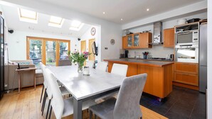 A modern kitchen with a central island, wooden cabinets, and built-in appliances. - The Tranquil Townhouse, by Veeve (London)